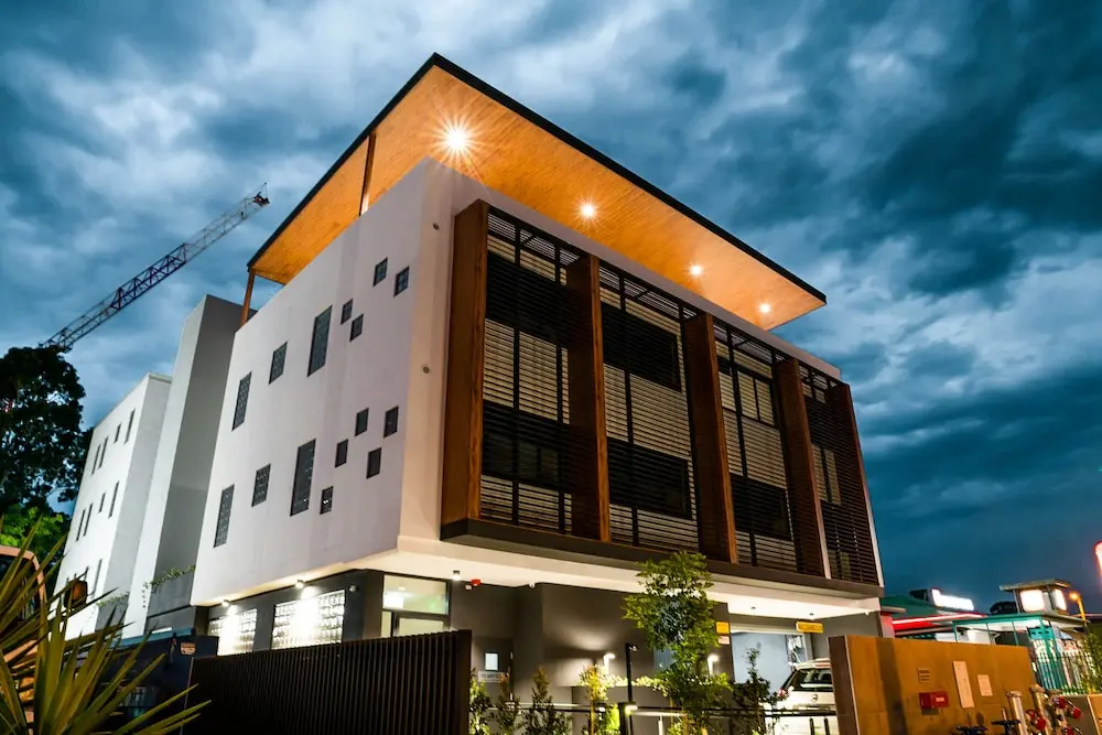Architectural building exterior at dusk with timber overhang and warm down-lights